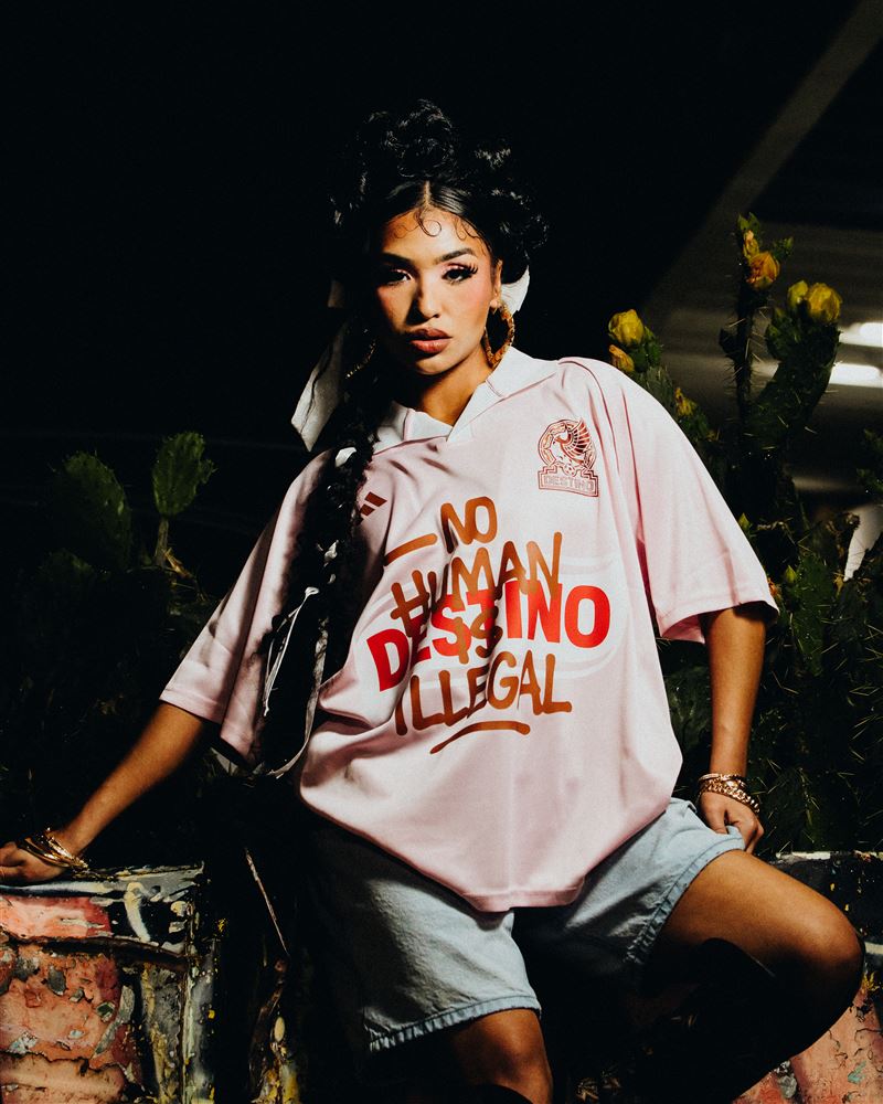 Woman in the pink Destino jersey seated in front of prickly pear cactus at night, lit by a small softbox