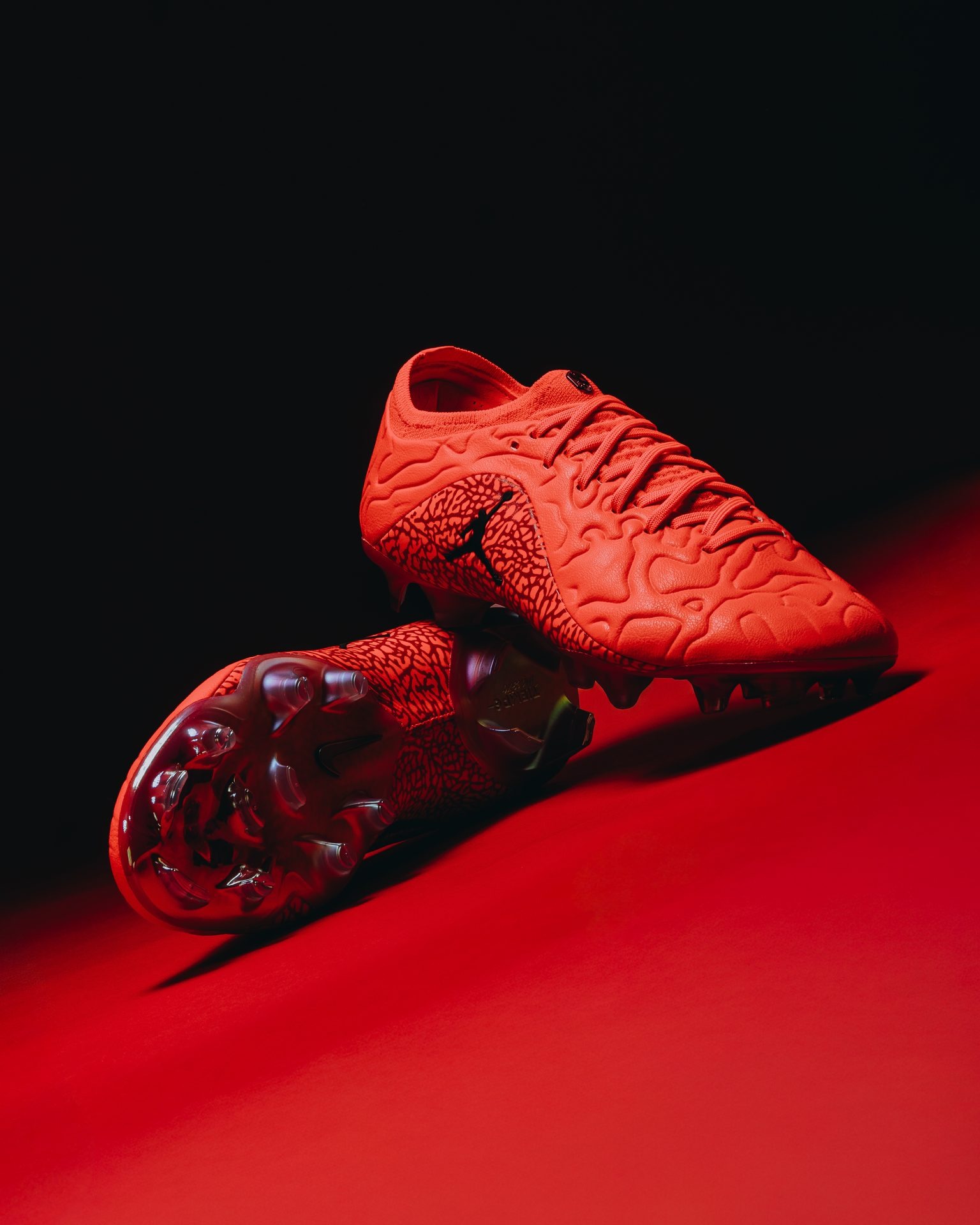 Jordan x Tiempo soccer cleats in dramatic red light